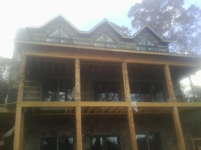 Dormers and porch framing on a large log home under construction — Roof Coating work by our crew in Vinita