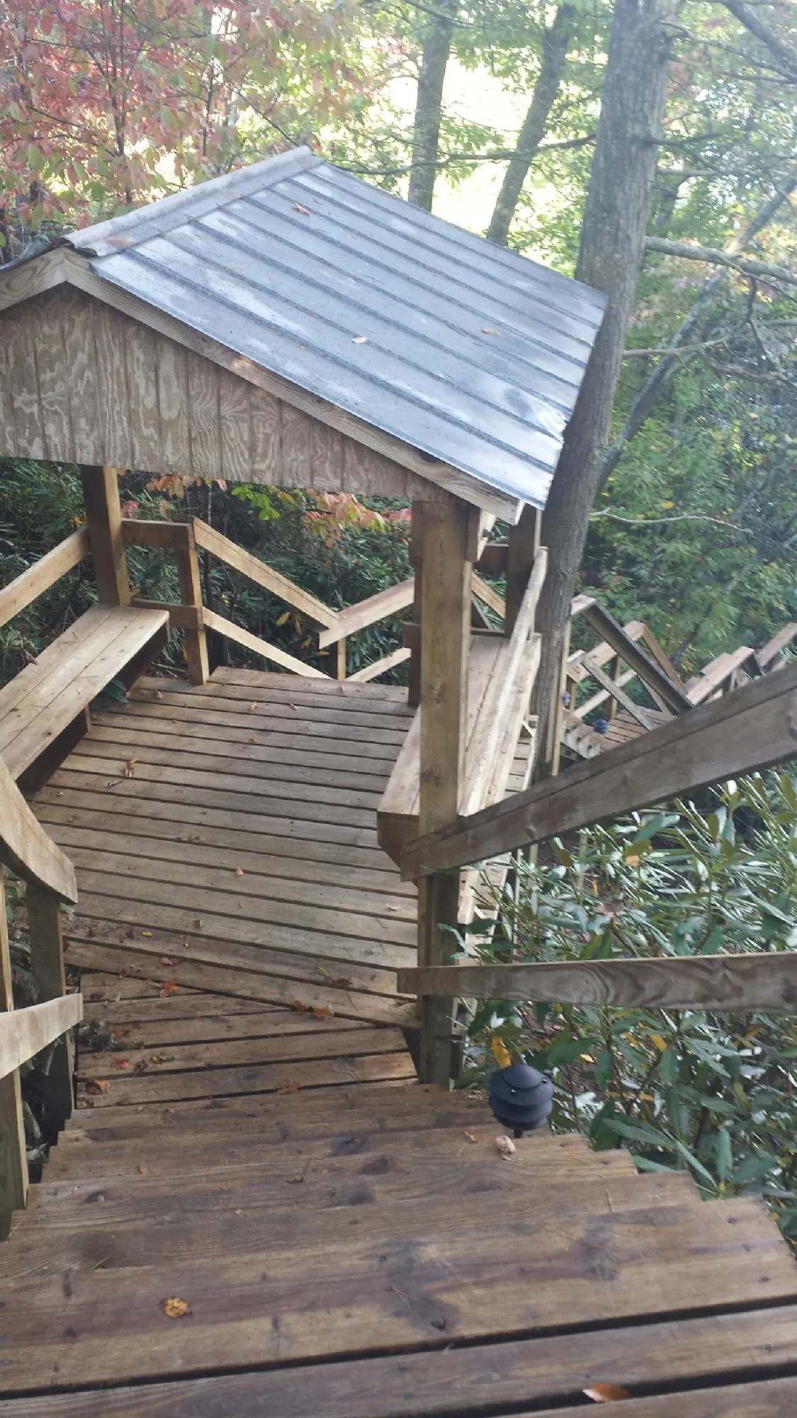 Metal roofed shelter over wooden steps on a wooded walkway — Skylight Repair & Installation work by our crew in Vinita