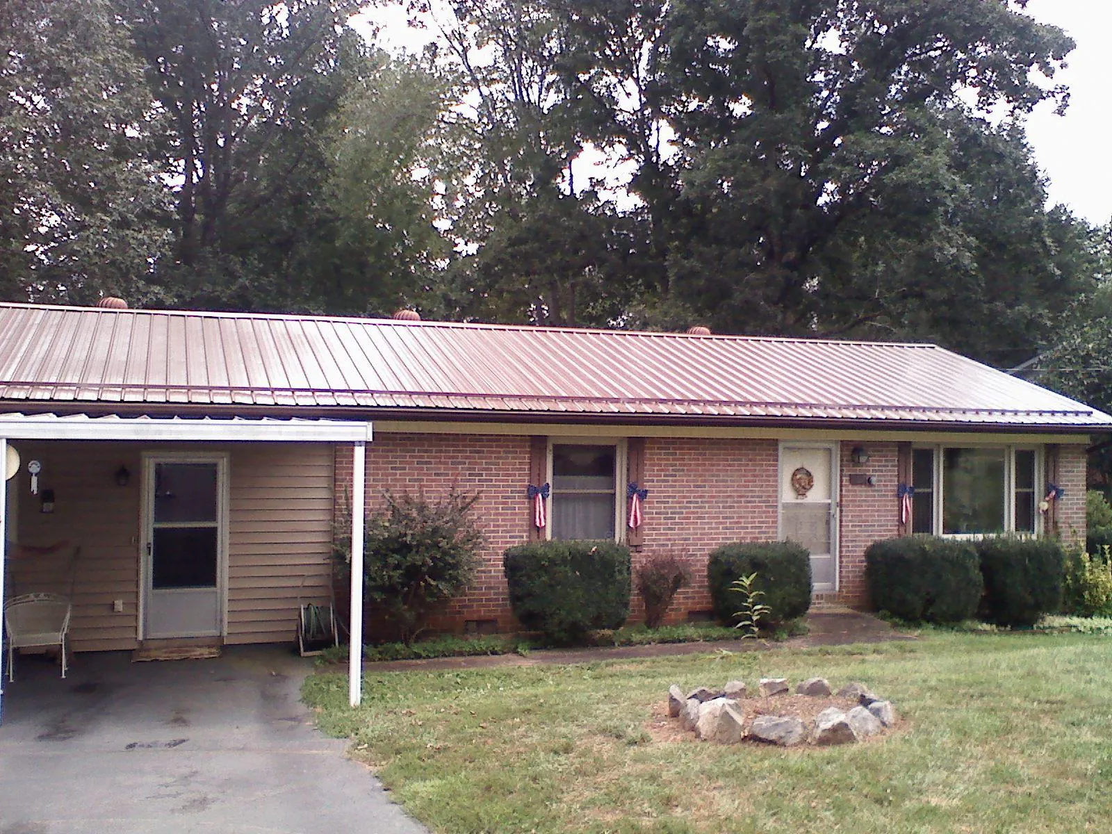Bronze metal roof and carport on a brick ranch home — Roof Repair work by our crew in Vinita