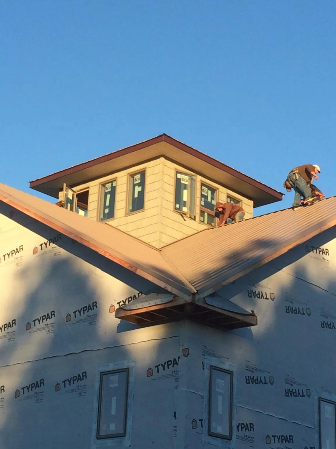 Roofers working around a rooftop cupola on a new metal roof at sunset — Roof Waterproofing in Vinita by Roofing Brothers